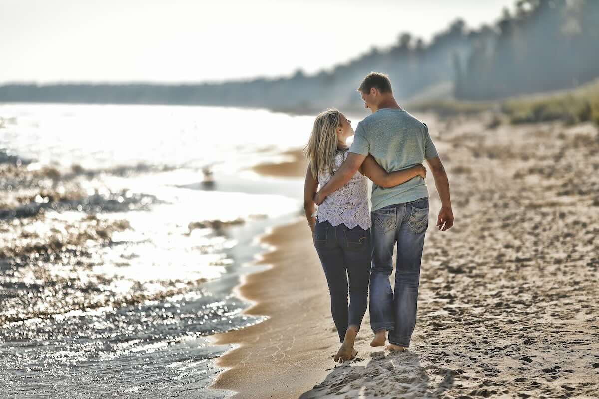 Couple walks on the beach during their engagement photography session.